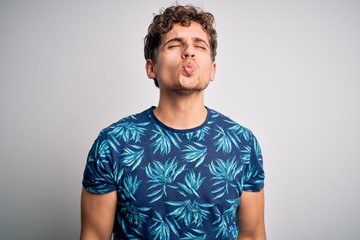 Obraz premium Young blond handsome man on vacation with curly hair wearing casual summer t-shirt looking at the camera blowing a kiss on air being lovely and sexy. Love expression.