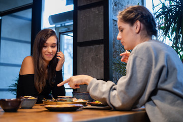 Two pretty young girls communicating in a cafe