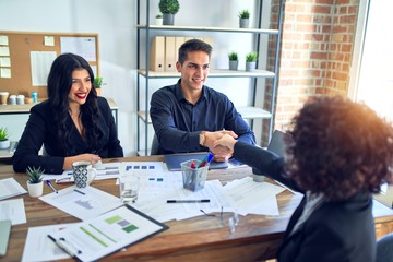 Group of business workers smiling happy and confident. Working together with smile on face shaking hands for agreement at the office