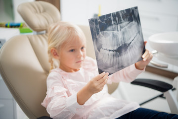 A little girl with an x-ray in a dentist chair. Dentistry, healt