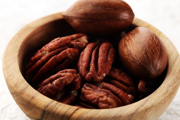 Pecan nuts on a rustic table and tasty pecan nuts in bowl