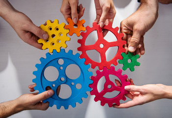 Business team connect pieces of gears. Teamwork, partnership and integration concept - obrazy, fototapety, plakaty