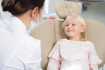Obraz premium A cute little girl at the dentist's office talking to her pediat