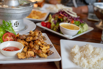 Fried mushrooms and rice and various dishes on a white plate placed on a wooden table