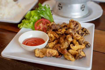 Fried shiitake mushrooms served on a white plate with chilli sauce