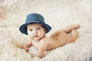 Happy young baby lying on tummy on a light bedspread.