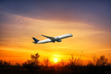 Fototapeta na wymiar Big aeroplane is taking-off on background of sunset.