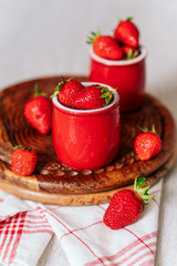 fresh strawberries in red pots on a wooden background, on a drop of water berries. healthy nutrition, vitamin charge, summer berries