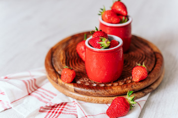 fresh strawberries in red pots on a wooden background, on a drop of water berries. healthy nutrition, vitamin charge, summer berries