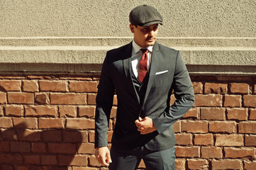 Portrait of retro 1920s english arabian business man wearing dark suit, tie and flat cap.