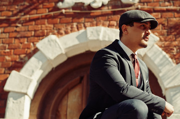 Portrait of retro 1920s english arabian business man wearing dark suit, tie and flat cap.