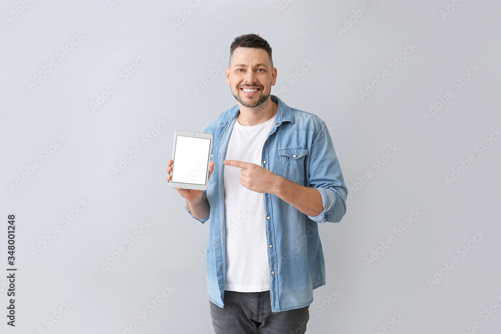 Poster handsome man with tablet computer on grey background
