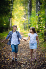 First love. Little boy and girl holding hands and smiling while walking outdoors in park