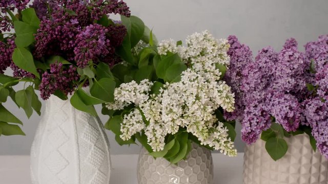 Vases with bouquets of beautiful lilac on table