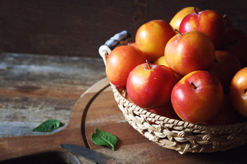 Yellow and red large plums in wicker basket