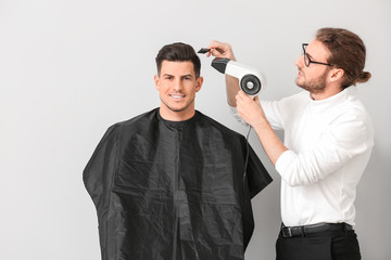 Fototapeta premium Young hairdresser working with client against white background