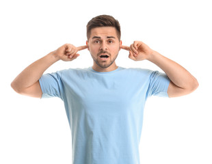Young man suffering from loud noise on white background