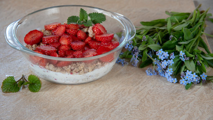 Muesli with yogurt and strawberries in a glass bowl