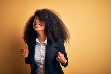 Young beautiful african american business woman with afro hair wearing elegant jacket very happy and excited doing winner gesture with arms raised, smiling and screaming for success. Celebration
