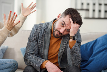 Nervous young man trying to doesn't listen to his girlfriend in the bedroom.