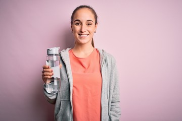Young beautiful sporty woman doing sport drinking bottle with water to refreshment with a happy face standing and smiling with a confident smile showing teeth