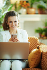 smiling modern woman with laptop and smartphone using app