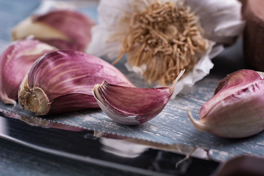 red garlic cloves on colorful wooden table - closeup