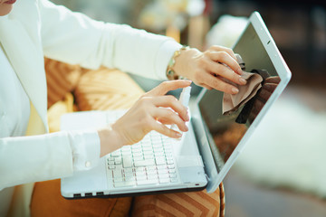 woman cleaning laptop screen with cleaning spray and cloth