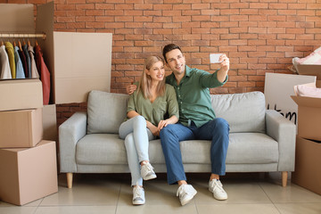 Obraz premium Young couple taking selfie in their new flat on moving day