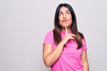Young beautiful brunette woman wearing casual pink t-shirt standing over white background Thinking...
