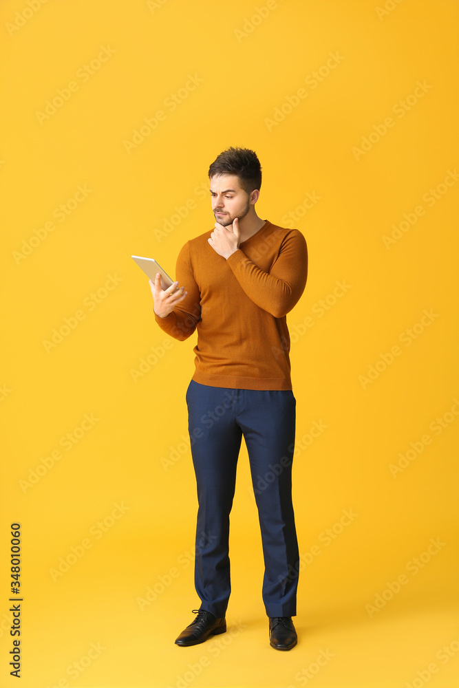 Poster thoughtful young man with tablet computer on color background
