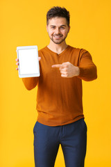 Young man with tablet computer on color background