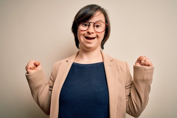 Young down syndrome business woman wearing glasses standing over isolated background celebrating...