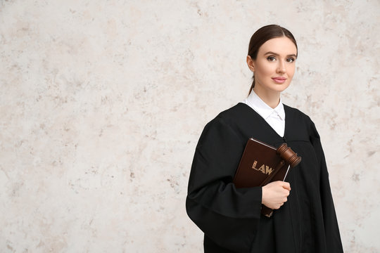 Female judge with book on light background