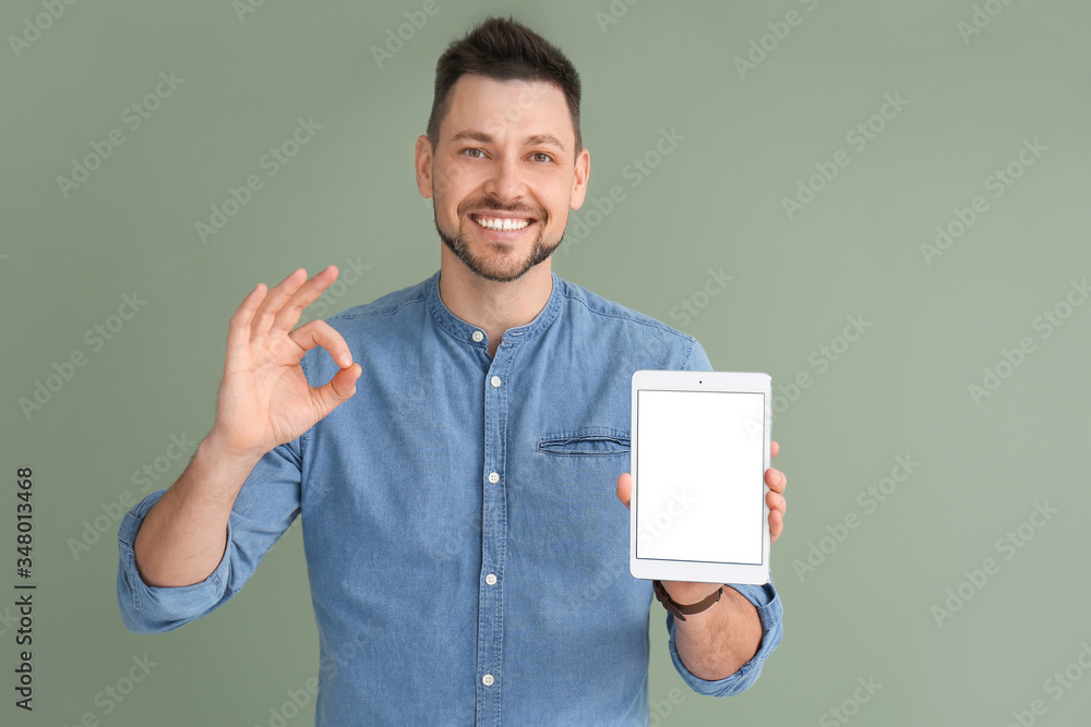 Poster handsome man with tablet computer showing ok gesture on color background