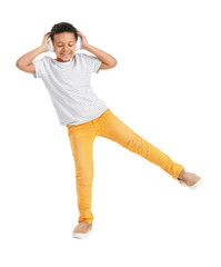 Little African-American boy listening to music and dancing against white background