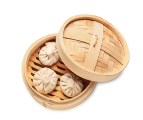 Steamer with uncooked dumplings on white background