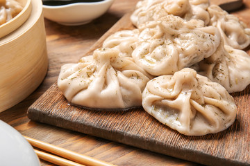 Fototapeta na wymiar Board with tasty dumplings on table, closeup
