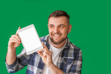 Young man with tablet computer on color background