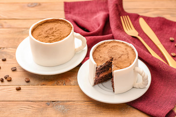Chocolate cakes in shape of coffee cups on wooden background