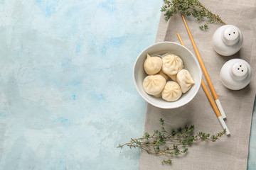 Bowl with tasty dumplings on color background