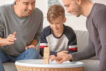 Happy gay couple with adopted child playing at home