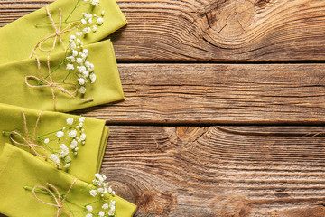 Napkins with floral decor on wooden background