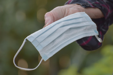 Disposable respiratory protective face mask being held by an outstretched hand.