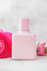 Obraz na płótnie Canvas Bottle of perfume with flowers on light background
