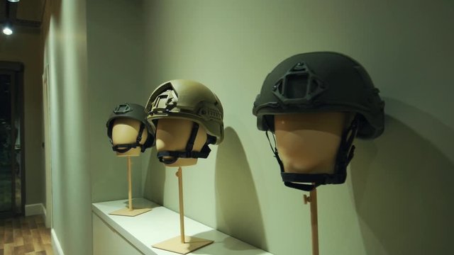 Three mannequin heads with soldier helmets as the camera does a hundred and eighty angle shot. military outfit showroom.