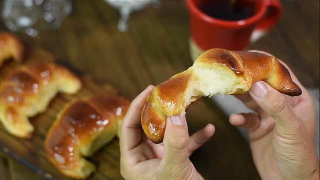 hands opening a fresh fluffy croissant croissant with table background served with breakfast or snack
