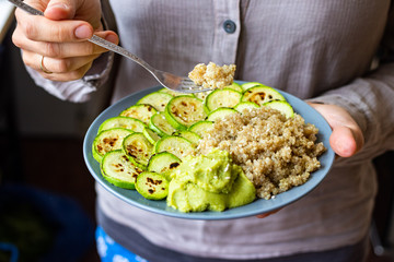 Baked roasted zucchini slices with cooked quinoa grain porridge on plate. Vegan balanced food.