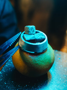 Grapefruit shisha bowl with moist tobacco inside and hot coals on top