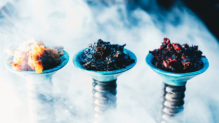 Side view of different kinds of hookah tobacco on smoky bar counter